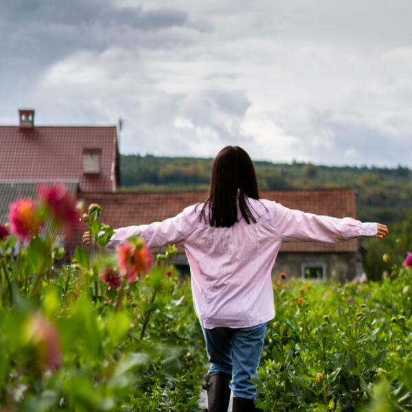 woman walking in flower bushes with alergies